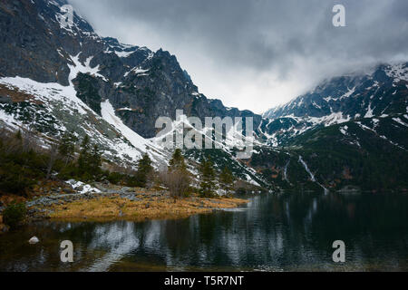 Berge mit Schnee und kleinen Wasserfällen zu einem See mit stürmischem Wetter fließt Stockfoto