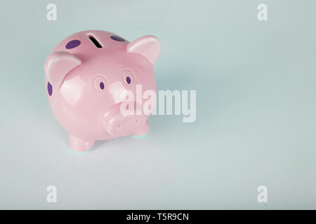 In der Nähe von rosa Sparschwein mit lila Punkte auf blauem Hintergrund mit Kopie Raum isoliert. Finanzen und Geld sparen. Stockfoto