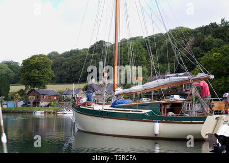 In Porthnavas Pool, Porthnavas Creek, den Helford River, Cornwall, Großbritannien: Eine Yacht verlässt den Kai Stockfoto