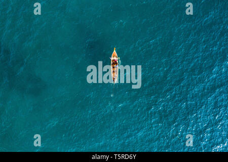 Ansicht von oben, aus der Vogelperspektive einen schönen long tail Boot segeln auf einem türkisfarbenen Meer. Phi Phi Islands, Maya Bay, Provinz Krabi, Thailand. Stockfoto