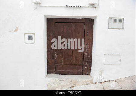 Alte groben braunen Holztür in weiß gestrichene Wand Stockfoto