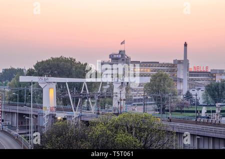 Rotterdam, Niederlande, 21. April 2019: Leuchten in der Dämmerung in der historischen Van Nelle Fabrik und auf der angrenzenden Eisenbahnbrücke über die Schie Stockfoto