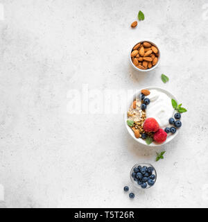 Müsli mit Joghurt und Beeren für ein gesundes Frühstück. Schüssel griechischen Joghurt mit Müsli, Mandeln, Blaubeeren und Erdbeeren, Ansicht von oben, kopieren. Stockfoto