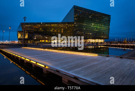 Reykjavik, Island - 08.20.2016: Die harpa von Reykjavik in der Nacht mit einem beleuchteten Holzsteg. Stockfoto