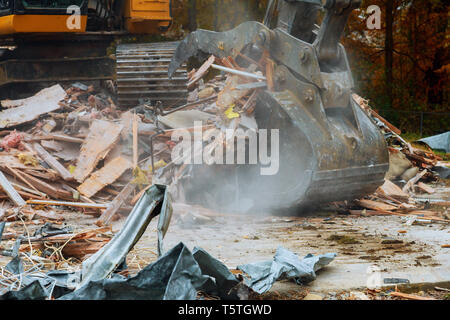 Altes Haus zerstört von einem grossen Bagger Baggerlader Holzbohlen und Trümmern und Ruinen abgerissen Stockfoto