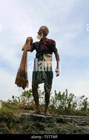 Ein Fischer Spaziergänge home entlang der Ufer des Flusses Rupsha in Khulna, Bangladesh, nach einem Tag, Fische zu fangen. Stockfoto