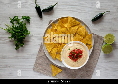 Hausgemachte cheesy Dip zu Nachos mit weißem Holz- Hintergrund. Flach, von oben, Overhead. Stockfoto