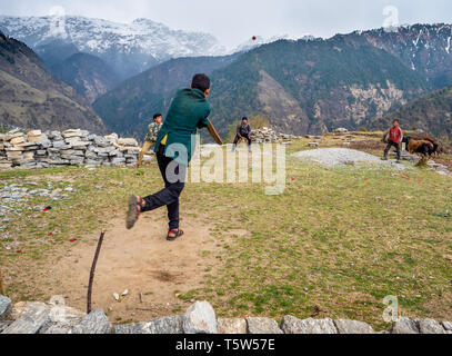 Junge Männer Cricket spielen, auf einer kleinen provisorischen Pitch durch steile Hänge in Saryu Jhuni Dorf im Tal des Uttarakhand Himalaya Indien umgeben Stockfoto