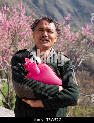 Glücklich lächelnde Guest house Keeper in einem kleinen Bergdorf im Tal Saryu in Uttarakhand nördlichen Indien tragen rosa Wärmflaschen Stockfoto