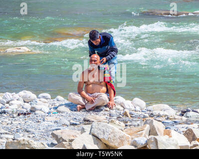 Der Mensch seinen Kopf rasiert durch die schnell fließenden Wasser des heiligen Fluss in Saryu Bageshwar im nördlichen Indien Stockfoto