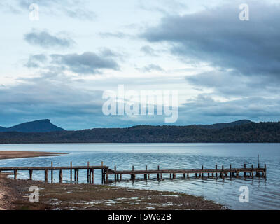 Wharf, ruhigem Wasser spiegelt den Abendhimmel, fernen dunklen Hügel, ein Herbstabend, Lake Hauroko, Fiordland National Park Stockfoto