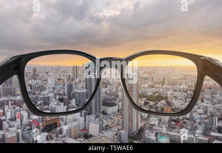 Blick durch die Brillen auf die Stadt Blick auf den Sonnenuntergang, auf der Linse mit verschwommenen Hintergrund fokussiert Stockfoto