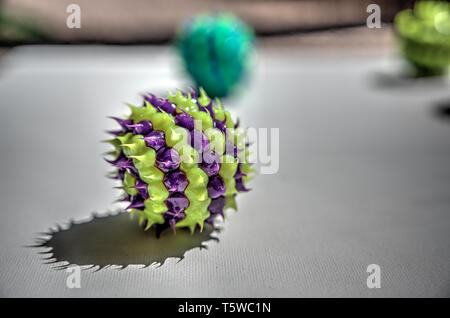 Lila und Grün gestreiften Ball mit Spikes auf weiße Oberfläche Stockfoto