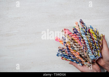 Geflochtene Fäden für Stickerei in weibliche Hände. Freier Text. Stockfoto