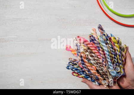 Geflochtene Fäden für Stickerei in weibliche Hände. Freier Text. Stockfoto