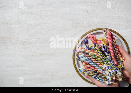 Geflochtene Fäden für Stickerei in weibliche Hände. Freier Text. Stockfoto