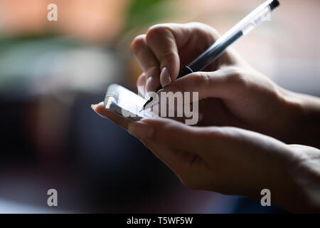 Nahaufnahme der Hand der Kellnerin mit Stift und Notizblock schreiben Besucher um Stockfoto