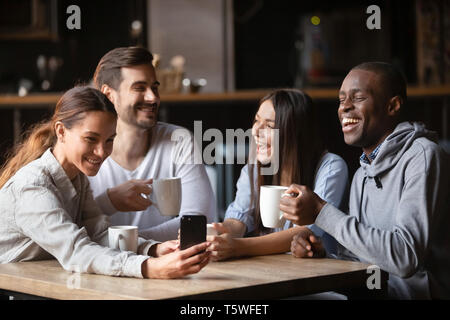Vier verschiedene Freunde Spaß mit Gadgets im Cafe sitzen Stockfoto