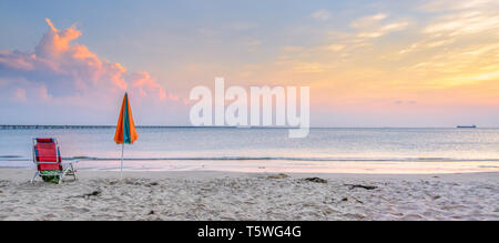 Liege und einen Schirm allein am Strand. Chesapeake Bay Bridge und Tunnel im Hintergrund Stockfoto