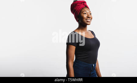 Lächelnd afrikanische Frau in Jeans auf weißem Hintergrund. Afrikanische Frauen mit einem Schal auf Kopf wickelte weg schauen. Stockfoto