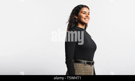 Seitenansicht der lächelnden Frau, die gegen den weißen Hintergrund. Portrait von fröhlicher junger Frau weg suchen. Stockfoto