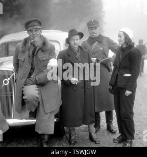 Der Winterkrieg. Ein militärischer Konflikt zwischen der Sowjetunion und Finnland. Sie begann mit einer sowjetischen Invasion im november 1939, als die sowjetische Infanterie die Grenze zum Karelischen Isthmus überquerte. Etwa 9500 schwedische Freiwillige nahmen am Krieg Teil. In der Mitte des legendären schwedischen Journalisten Barbro Alving. Bereits ein erfahrener Kriegsberichterstatter, der vom spanischen Bürgerkrieg berichtete. Hier der Karelische Isthmus Finnland im Dezember 1939 mit finnischen Soldaten, die sie begleiten sollten. Er verließ Erik Wästberg, schwedischer Journalist der Tageszeitung. Foto Kristoffersson Ref. 100-5 das Auto ist ein Volvo PV Stockfoto