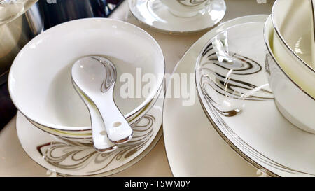 Stapel von keramischen Platten Schalen, Löffel China Porzellan elegantes Weiß Grau Dekoration Blumen muster antikes Geschirr auf weißen Tisch Stockfoto