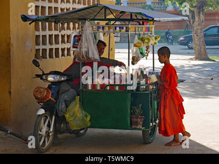 Außerhalb der Stadtmauern der Altstadt von Wat Kampong Thom ein Kind Mönch kauft einen Snack Form ein Lebensmittel Anbieter. Kampong Thom, Kambodscha. 19-12-2018 Stockfoto