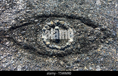 Symbolische Auge aus Steinen und Sand auf einem Sommer Pebble Beach - Begriff des Big Brother, Allgegenwart Gottes oder öffentliche Überwachung. Stockfoto