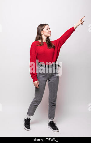 Junge Frau das Tragen der roten Pullover miling und die Kamera zeigt mit der Hand und den Fingern zur Seite. Stockfoto