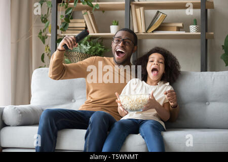 Afrikanischen Vaters Tochter sitzen auf der Couch feiern Fußball Mannschaft gewinnen Stockfoto