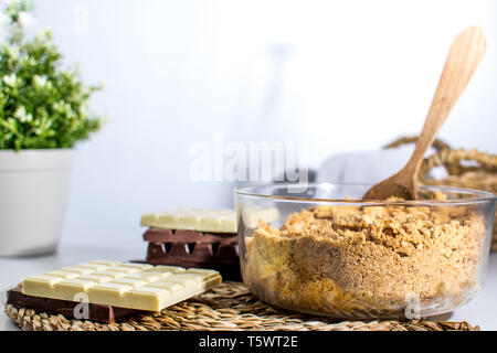 3 Schokoladen Kuchen Torte Zutaten auf den Tisch. Küche mit weisser, dunkler und Milchschokolade. Haselnüsse jar. Kekse Teig Stockfoto