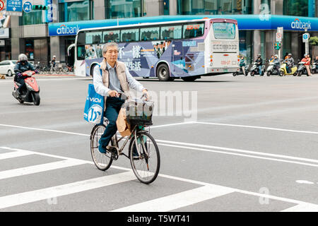 Taipei, Taiwan - 26 April 2019: Taiwanesische älterer Mann mit dem Fahrrad über die Straße an der Kreuzung während der Rushhour in Taipei City Stockfoto