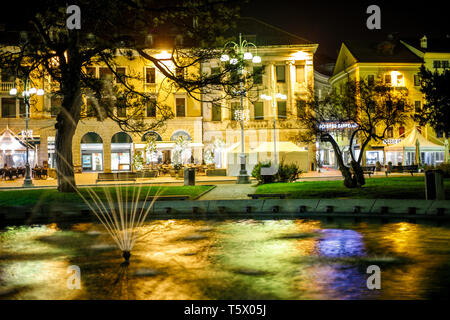 Bunter Blick auf einem riesigen Brunnen mit alten Dekoration und einige Gebäude im Hintergrund in einem italienischen Dorf in der Nacht Stockfoto