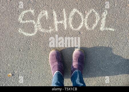 Das Wort Schule auf dem Asphalt und die Füße der Schüler. Zurück zur Schule Stockfoto