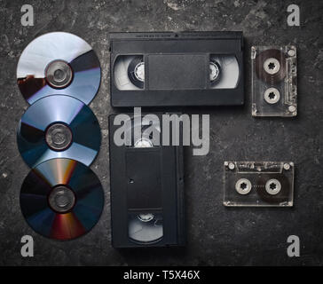 Flach Videokassetten, CDS, audio Kassette auf einem schwarzen Betonoberfläche. Retro media Technologie der Vergangenheit an. Ansicht von oben. Stockfoto