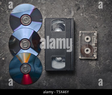 Flach Videokassetten, CDS, audio Kassette auf einem schwarzen Betonoberfläche. Retro media Technologie der Vergangenheit an. Ansicht von oben. Stockfoto