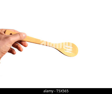 Die Hand eines Mannes hält einen Löffel aus Holz - Spachtel auf einem weißen Hintergrund. Küche Tools für das Kochen. Stockfoto