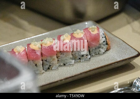 Lachs Sushi Roll mit grünen Kaviar Fisch Eier oben auf einer Platte in ein Sushi Restaurant. Stockfoto