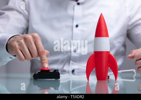 Der Geschäftsmann Hand mit Raketen durch Drücken der roten Taste Stockfoto