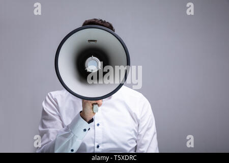 Mann tun Durchsage über Megaphon vor grauem Hintergrund Stockfoto