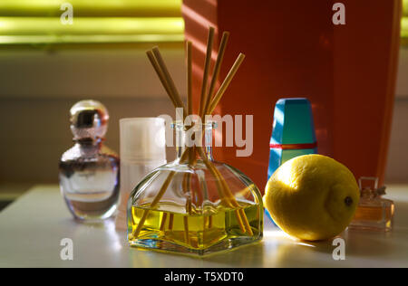 Duft diffusor Glas mit Reed sticks zwischen Parfum Flakons, natürlichen Duft der Zitrone Stockfoto