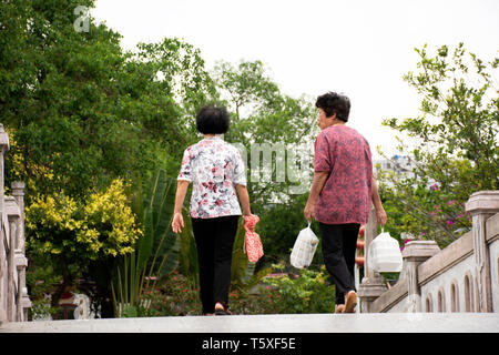 Chinesische Alte Frauen Menschen zu Fuß holding Essen in Plastiktüte entspannen auf Brücke im Garten an der Zhongshan Park in Shantou Stadt oder Swatow Stadt am 9. Mai, 2. Stockfoto