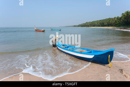 Nicht identifizierte Fischer neben Fischerboot auf Chera Strand (Thottada) zum Arabischen Meer an einem sonnigen Tag in Thottada, Kannur, Kerala, Indien. Stockfoto