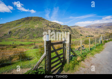 Majestätischen Blick auf das malerische Tal in Snowdonia, North Wales, UK, im Frühling. hölzerne Tor im Vordergrund, Gipfel und blauen Himmel im Hintergrund. Stockfoto