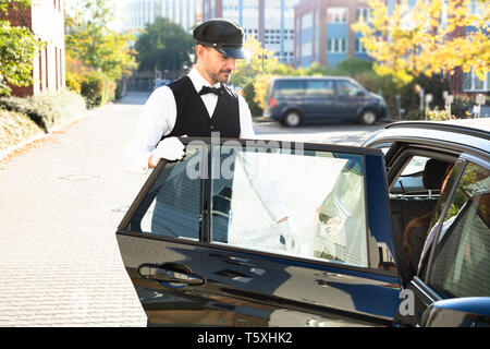 Nahaufnahme der Hand Öffnen der Fahrzeugtür Während lächelnde junge Frau sitzt im Auto. Stockfoto