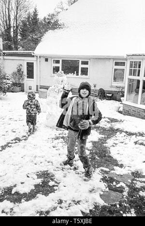 9 Jahre alter Junge wirft einen Schneeball in die Kamera, Medstead, Hampshire, England, Vereinigtes Königreich. Stockfoto