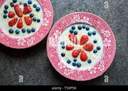 Britisches Frühstückszerealien: Traditionelle Keramikgerichte mit Haferbrei, dekoriert mit frischem Obst, Erdbeeren und Blaubeeren. Stockfoto