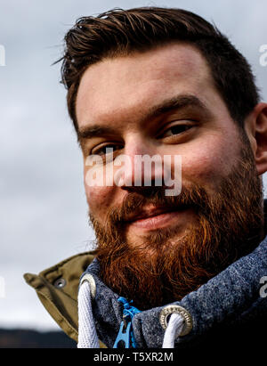 Junge attraktive bärtiger Mann mit dunklem Haar und einen Pullover im Park mit einem ernsten Blick Stockfoto