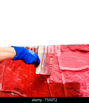 Die Farbe der Wand in Rot mit einer großen Breite Pinsel. Stockfoto